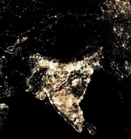Night-time view of the Asian continent from space, highlighting the urban lights of India and surrounding regions. The light clusters indicate densely populated and developed areas. India